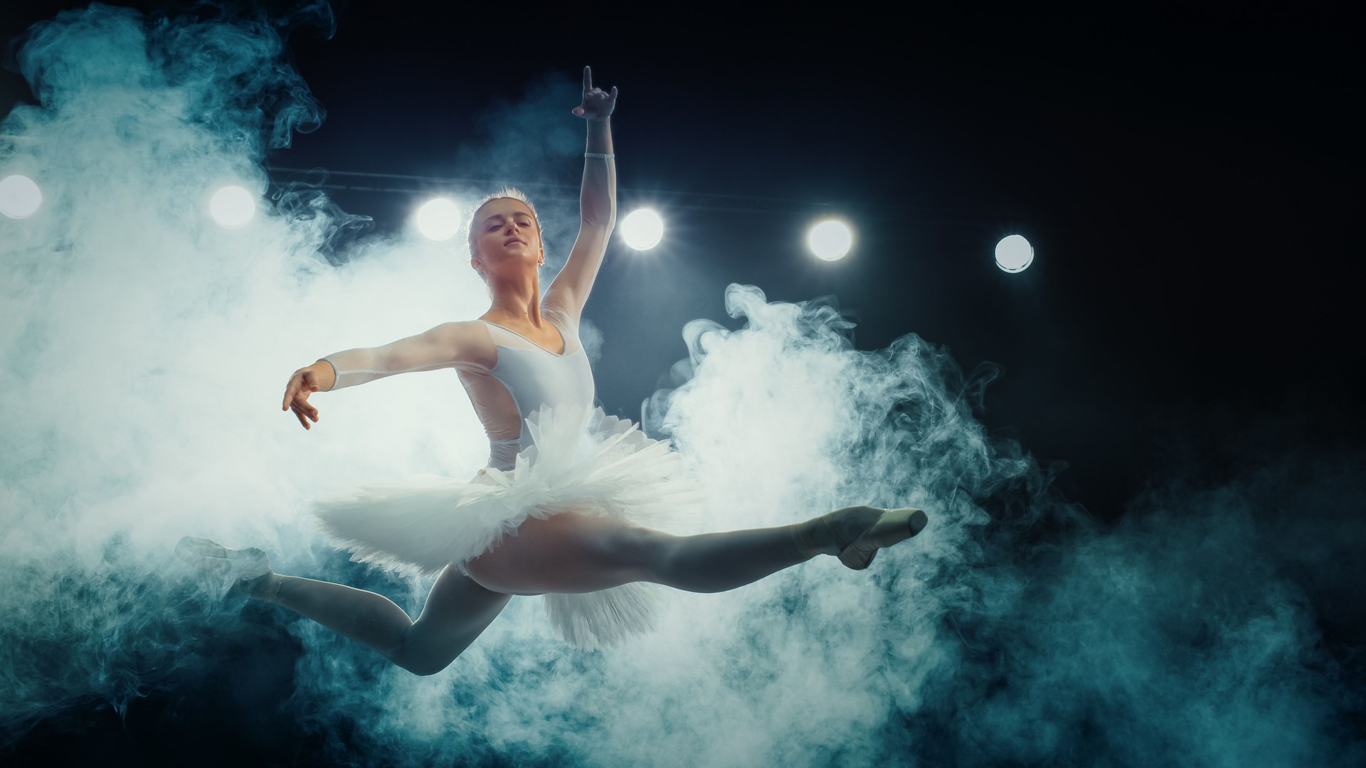 Elegant Ballet Dancing Ballerina White Tutu Performs Breathtaking Grand Jeté Amidst Dramatic Stage Smoke and Lights,  Her Grace and Strength in Captivating Ballet Performance.